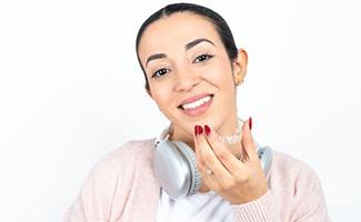 Smiling woman holding her Invisalign aligner
