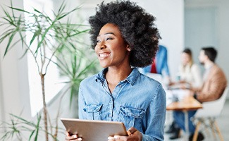 Woman smiling while holding tablet in office