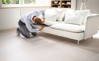 Man searching under couch cushions for lost Invisalign aligner