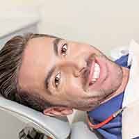 Male dental patient sitting back in dental chair smiling