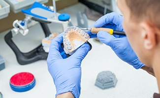 Lab technician painting replacement teeth