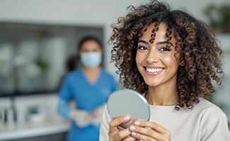 Woman smiling while holding small mirror