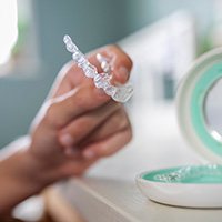 Teen putting clear aligner in case with mirror