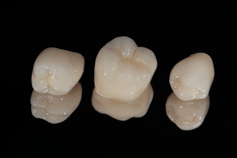Ceramic dental crowns laying against a mirror